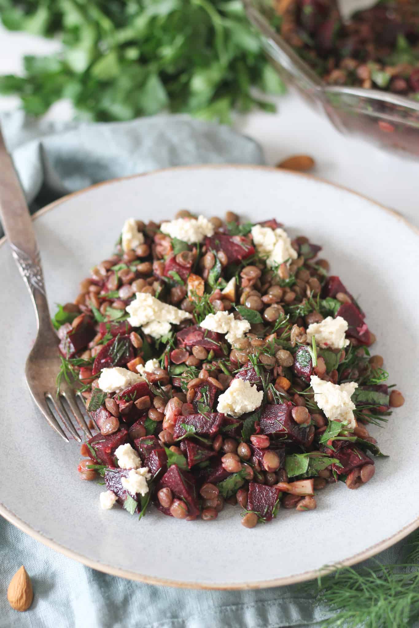 Lentil and beetroot salad with tofu feta and fresh herbs in a blue plate
