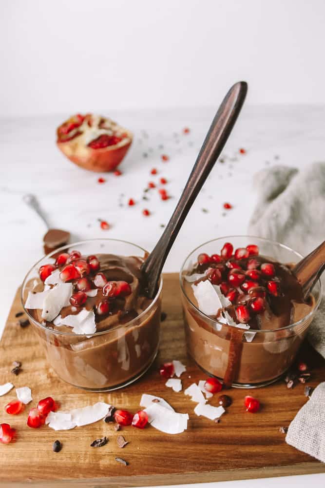 mousse au chocolat à la patate douce dans deux verres, garnie de grenade et de noix de coco