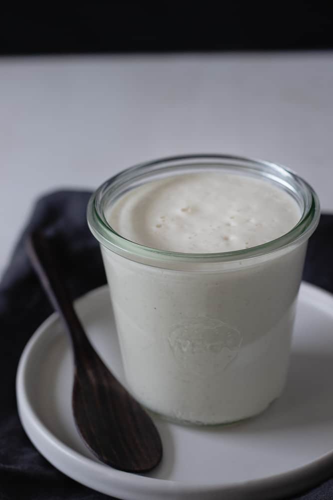 vegan cream in glass jar with a wooden spoon