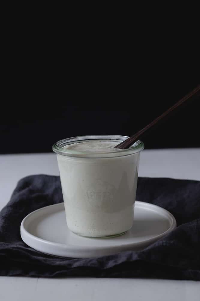 vegan cream in glass jar with a wooden spoon