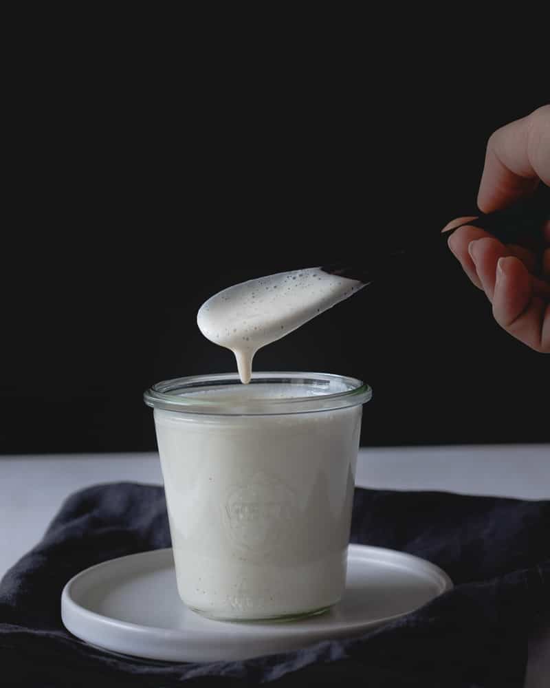 crème végane dans un pot en verre avec cuillère de bois qui sort