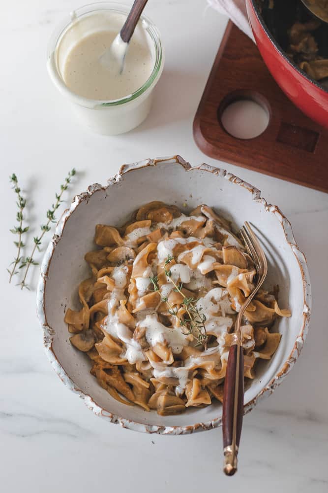 mushroom stroganoff in bowl seen from above topped with vegan cream and fresh thyme