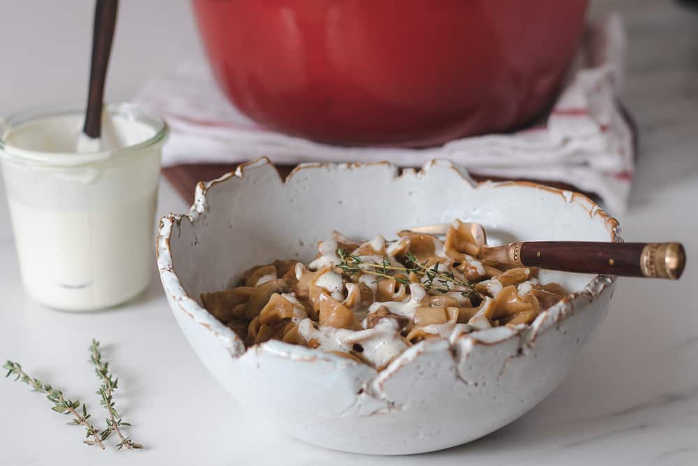 mushroom stroganoff in bowl topped with vegan cream and fresh thyme