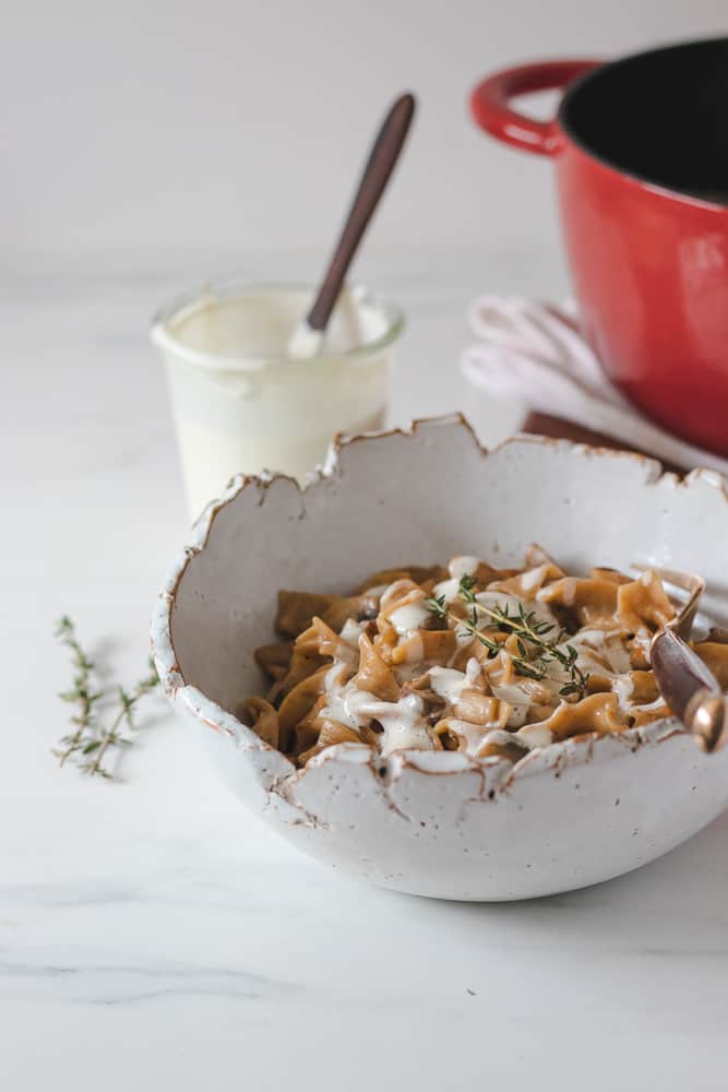 mushroom stroganoff in bowl topped with vegan cream and fresh thyme